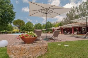 a patio with a flower pot and an umbrella at Agriturismo Oasi Torre Del Colle in Bevagna