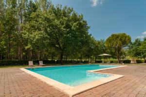 una piscina en un patio de ladrillo con árboles en Agriturismo Oasi Torre Del Colle, en Bevagna