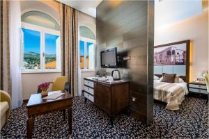 a hotel room with a bed and a desk and a tv at Hotel Lapad in Dubrovnik