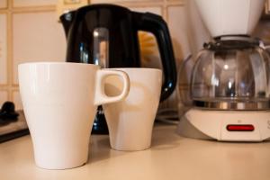 two white cups sitting on a counter next to a blender at Taonasi Taormina Apartments in Taormina