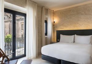 a bedroom with a large bed and a balcony at EME Catedral Hotel in Seville