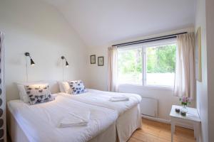 a white bedroom with a bed and a window at Hälleviks Havsbad in Hällevik