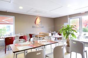 um restaurante com mesas e cadeiras e uma placa na parede em Campanile Chalon sur Saône em Chalon-sur-Saône