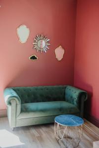 - un canapé vert dans une pièce aux murs rouges dans l'établissement La Maison Augustine, à Gap