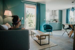 a woman sitting on a couch in a living room at La Maison Augustine in Gap