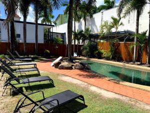 um grupo de cadeiras sentadas ao lado de uma piscina em Mumma's Hostel Cairns em Cairns
