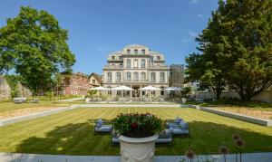 a large white house with a yard with couches at Hôtel Mille Pas in Voiron