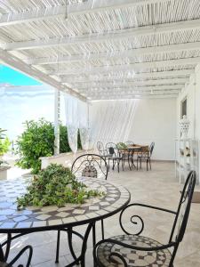 d'une terrasse avec des tables et des chaises et un plafond blanc. dans l'établissement Casa Poesia, à Torre San Giovanni