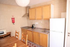 a kitchen with wooden cabinets and a white refrigerator at Salema Beach Home in Salema