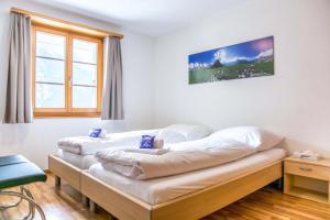 two beds in a room with a window at Apartment Dolomit EG - GRIWA RENT AG in Grindelwald