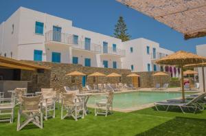 a pool with chairs and umbrellas in front of a building at Ostria Hotel & Apartments in Gavrio