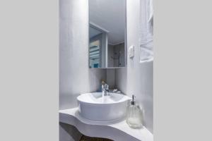 Baño blanco con lavabo y espejo en Myrtia House Skopelos, en Skopelos Town