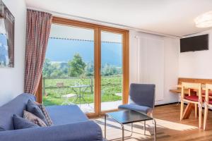 a living room with a blue couch and a table and a window at Hapimag Ferienwohnungen Andeer in Clugin