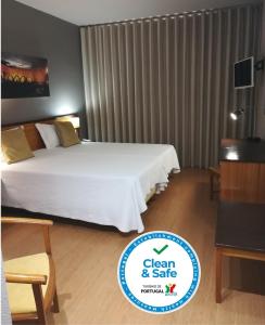 a hotel room with a bed and a sign for clean and safe at Hotel Dom Vilas in Braga