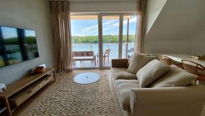 a living room with a couch and a view of the water at Apartament Blisko Natury in Tomaszkowo