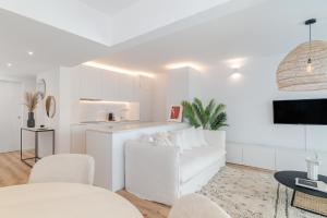 a white living room with a white couch and a kitchen at Casa Boma Lisboa - Architect Apartment with Private Terrace - Alcantara III in Lisbon