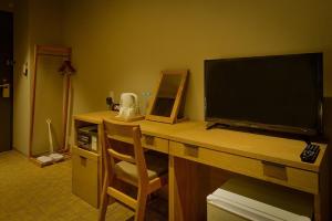einen Schreibtisch mit einem TV und einem Stuhl in einem Zimmer in der Unterkunft ikoi HOTEL in Kyoto