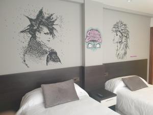 2 camas en una habitación con carteles en la pared en Hotel Arts - Gasteiz Centro, en Vitoria-Gasteiz