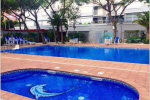 a large blue swimming pool with blue chairs and a building at Apartamento primera línea de Mar Enjoy the view in Blanes