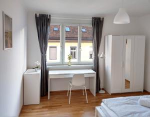 Schlafzimmer mit einem Schreibtisch und einem Fenster mit einem Stuhl in der Unterkunft Helle und gemütliche Wohnung in zentraler Lage in Graz