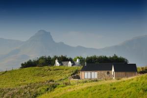a house on a hill with a mountain in the background at Skye Eyrie in Staffin