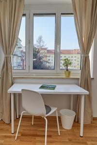 einen weißen Schreibtisch und einen Stuhl vor einem Fenster in der Unterkunft Gemütliche Wohnung in zentraler Lage in Graz