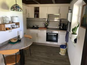 una cocina con armarios blancos y una mesa con sillas. en Kleine Ferienwohnung bei Kappeln an der Schlei en Kappeln