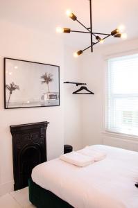 a white bedroom with a bed and a fireplace at Boutique Getaway, edge of Old Town- 4min walk to beach in Margate