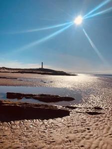 a beach with the sun shining on the sand at Skerry View - Overlooking the Moray Firth - close to Beaches, Harbour, Shops and Restaurants in Lossiemouth