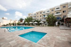 a swimming pool in front of a building at DebbieXenia Hotel Apartments in Protaras