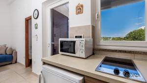 a kitchen with a microwave on a counter with a window at Rona Apartment Zdravko in Barbariga