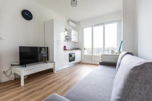 ein weißes Wohnzimmer mit einem TV und einem Sofa in der Unterkunft AppartHotel T3 EpicServices Saint-Charles in Marseille