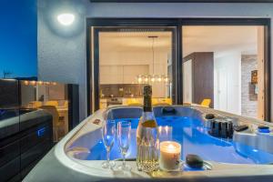 a bath tub with a bottle of wine and two glasses at Mediteran luxury penthouse with jacuzzi in Mandre +37 photos