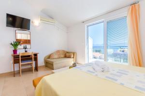 a bedroom with a bed and a desk and a window at Knezovicapartments in Živogošće