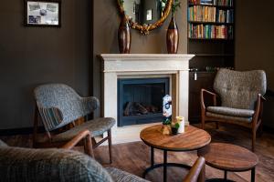 een woonkamer met een open haard, stoelen en een tafel bij Hotel Het Wapen van Drenthe in Roden