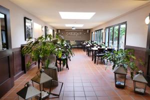 ein Restaurant mit Tischen, Stühlen und Topfpflanzen in der Unterkunft DAS Steeps Ihr Brauhaus und Hotel in Köln