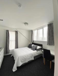 a bedroom with a bed and a desk and windows at Alderberry Lodge in Newquay