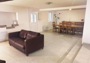 a living room with a brown leather couch and a dining room at Gîte en Béarn entre Océan et Montagne classé 4 Etoiles in Labeyrie