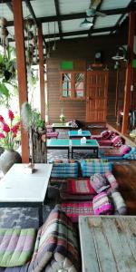 una habitación con muchas mesas y almohadas en el suelo en Baan Ing Suan, en Amphawa