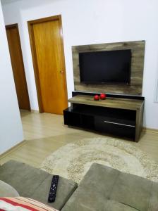 sala de estar con TV de pantalla plana y sofá en AP Confortável San Inácio en Santo Ângelo