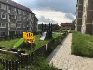 einen Spielplatz mit Rutsche im Gras neben einem Gebäude in der Unterkunft Apartman Q11 in Sokolov