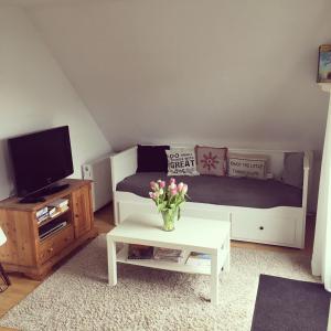 a living room with a bed and a table with flowers at Spechtstraße 65 Ferienwohnung in Nordhorn
