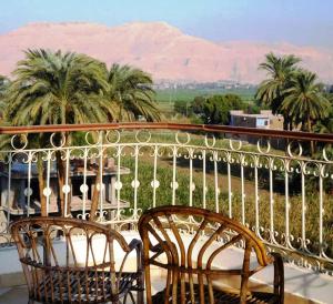two chairs on a balcony with palm trees and mountains at Leyla Eco Resort in Luxor