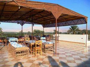 a patio with tables and chairs under a roof at Leyla Eco Resort in Luxor