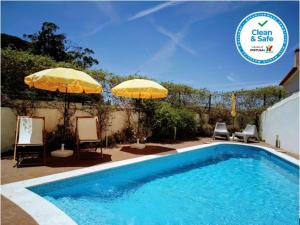 a swimming pool with two umbrellas and two chairs at Casa de Atalaia in Palmela