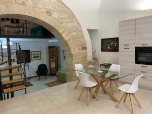 a dining room with a table and white chairs at OpenSpace Beneventano in Scicli