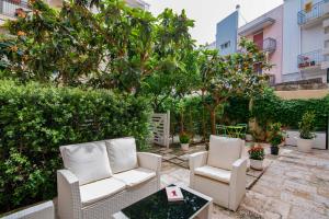 a patio with two chairs and a table and trees at Al Giardino Del Nespolo in Polignano a Mare