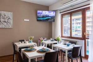 een eetkamer met tafels en stoelen en een tv aan de muur bij Momo Central Rome 3 in Rome