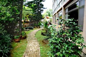 un camino de ladrillo en un jardín junto a un edificio en Very Happy Homestay, en Pingxi