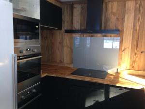 una cocina con electrodomésticos negros y armarios de madera en chalet clémentine, en La Tania